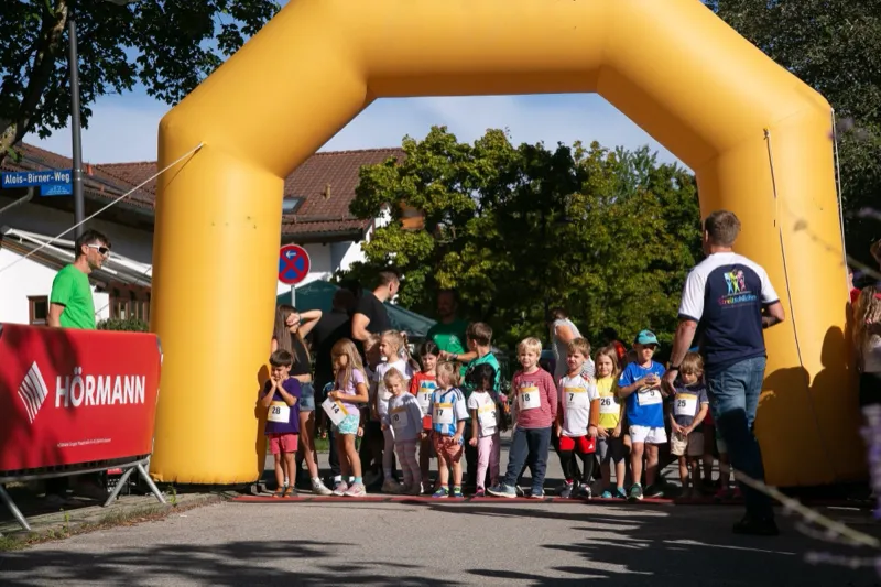 Bambini-Lauf: Kinder stellen sich unter dem gelben Startbogen auf, dahinter Eltern und Helfer.